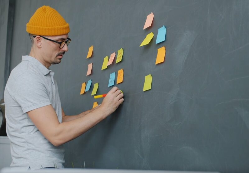 man attaching sticky notes to board