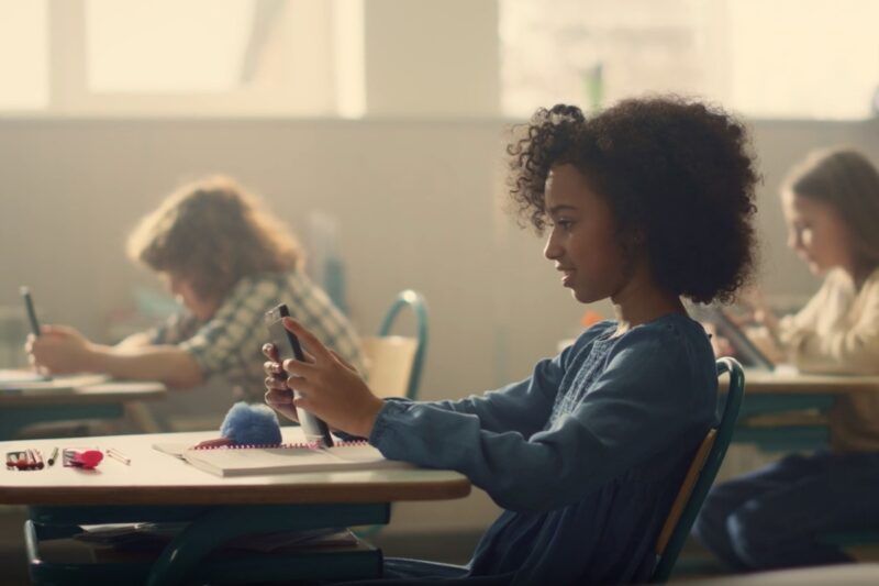 girl sitting in school with smartphone in hands